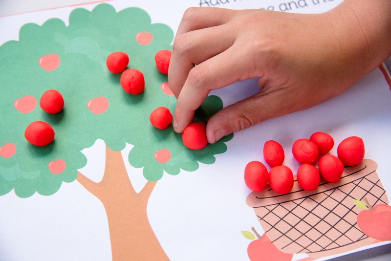 child playing with colorful apple tree seasons play dough mat
