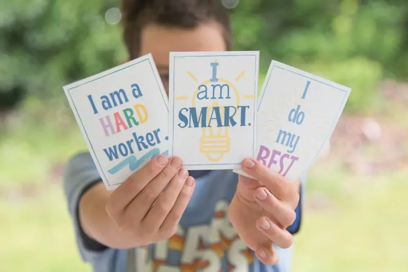 child holding printable cards with daily affirmations on them