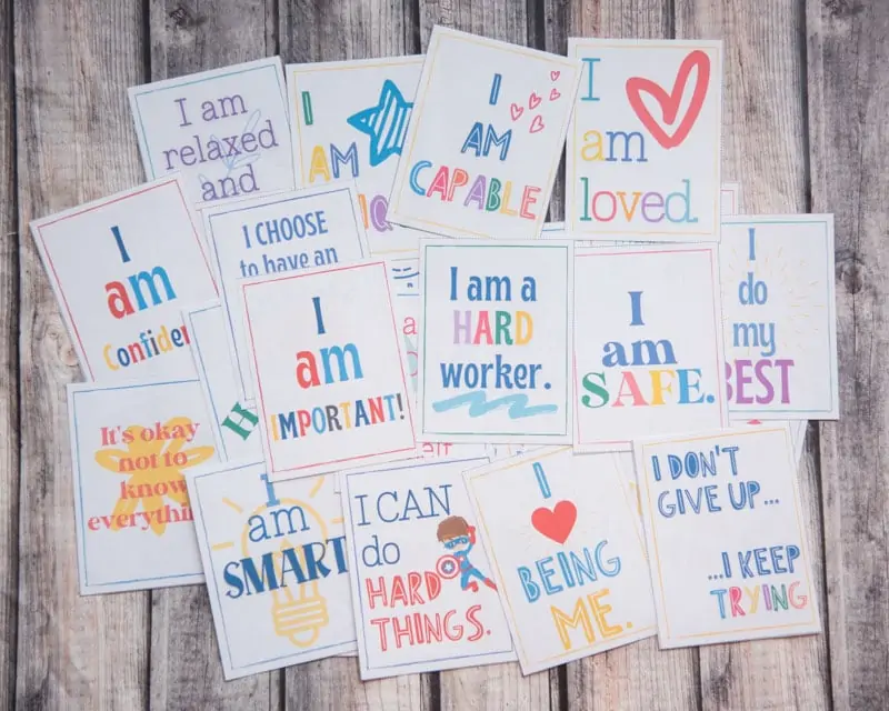 printed affirmations cards for children laid out on a wooden surface