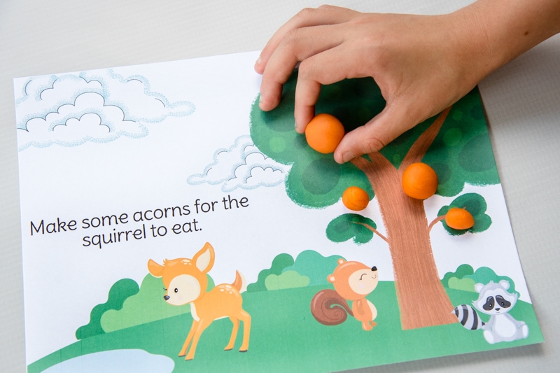 child hand playing with colorful spring animals play dough mat