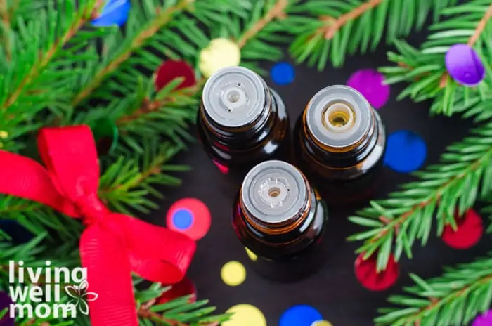 top view of three opened essential oil bottles in the midst of christmas greenery