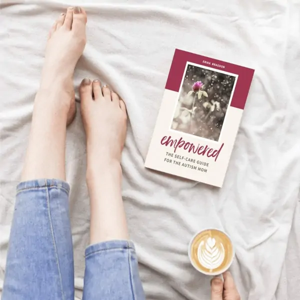 A woman sitting on a bed with a cup of coffee and a book for moms with autistic children