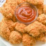 crispy healthy chicken nuggets on white plate with ketchup dipping sauce
