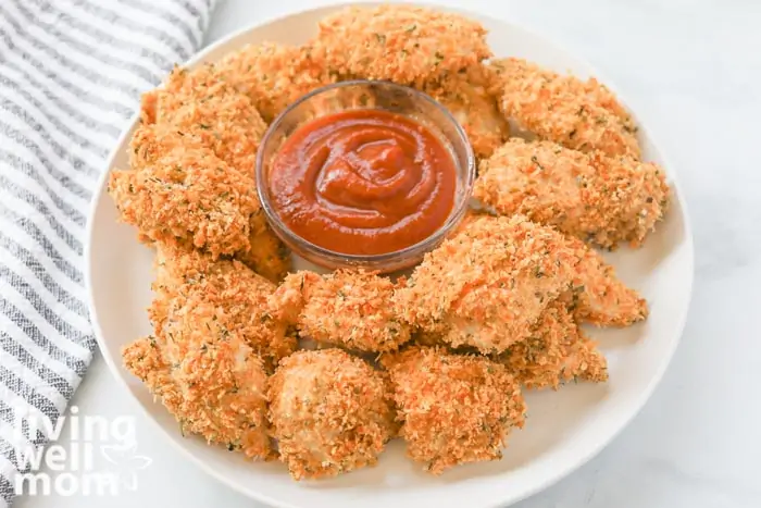 crispy chicken nuggets on a white plate with container of dipping sauce