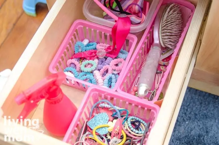 pink plastic organizers holding kids hair accessories and tools