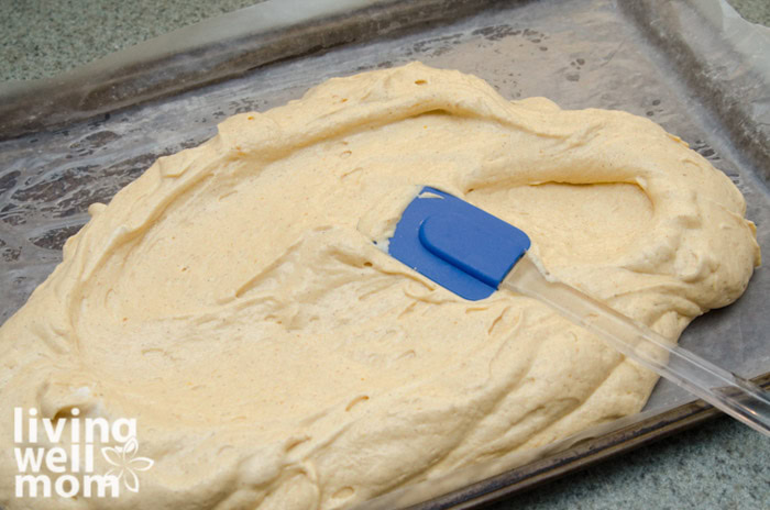 spreading pumpkin roll batter onto lined baking sheet