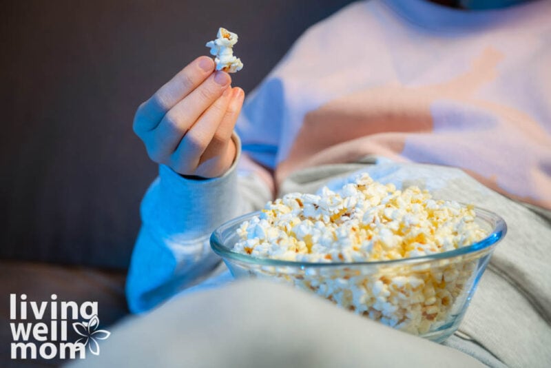 someone eating a bowl of popcorn, with one piece in their hand