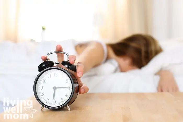 Busy mom hitting snooze on an alarm clock