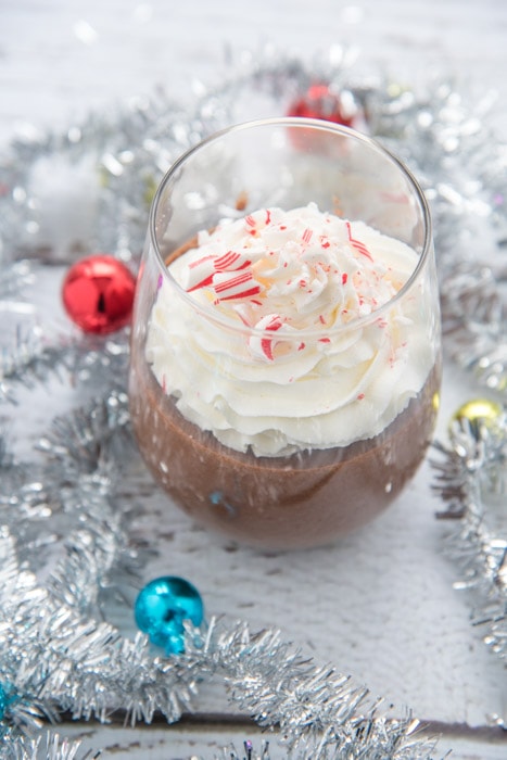 chocolate peppermint cream pudding in a glass topped with whipped cream and crushed candy canes