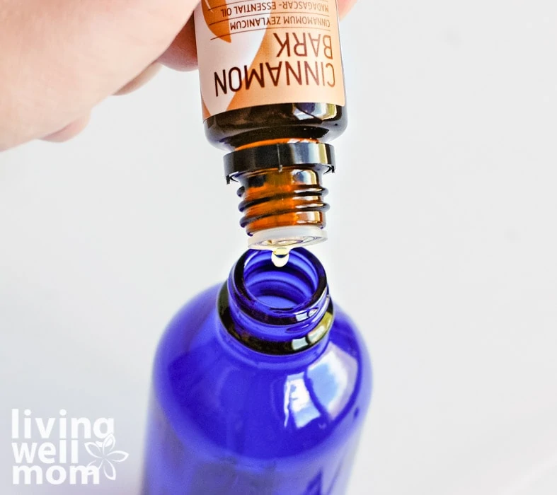 cinnamon bark oil dropping into blue glass bottle