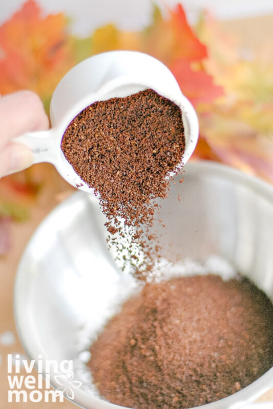 measuring cup of coffee grounds pouring into mixing bowl