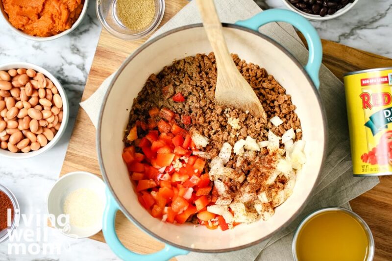 ground beef with diced onions and red bell pepper on top next to a bowl of beans