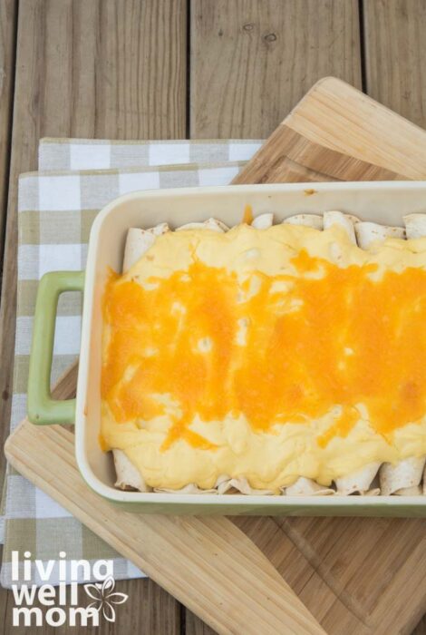 green baking pan filled with homemade enchiladas with sour cream sauce