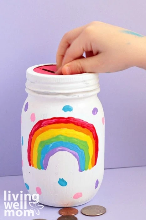 child putting money into DIY mason jar piggy bank