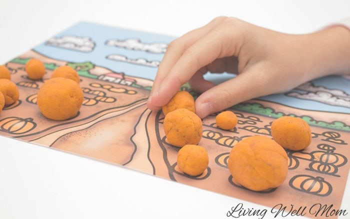 balls of orange playdough being placed on an activity mat