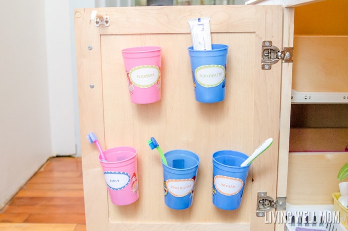 plastic cups mounted inside cabinet for toothbrush storage