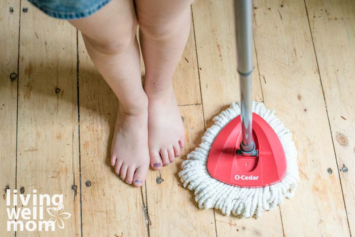 child standing next to mop