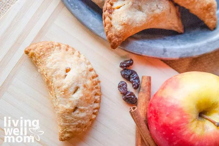 apple, raisins, and cinnamon sticks next to a plate of apple tarts