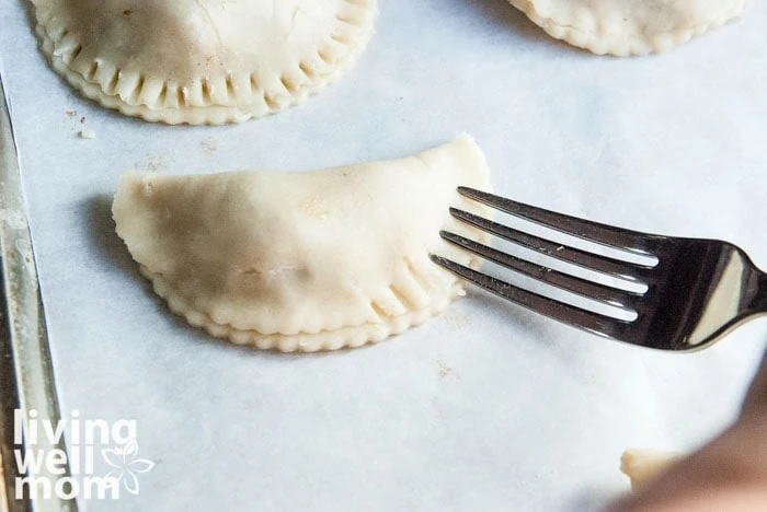 securing the edges of mini apple pies before baking