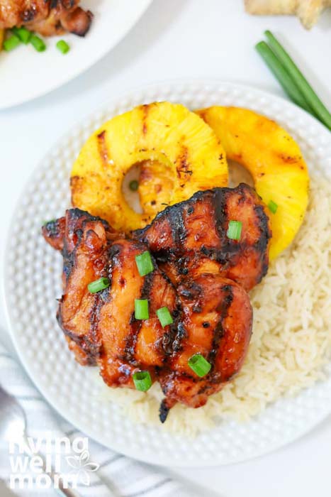 a dinner plate with a serving of grilled chicken and pineapple on a bed of rice