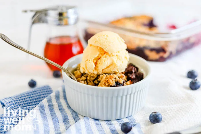 a scoop of vanilla ice cream atop blueberry maple crumble