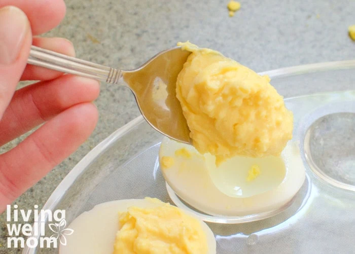 adding a dollop of yolk mixture into boiled egg halves