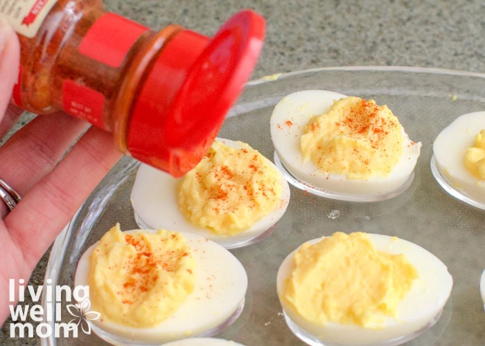 sprinkling paprika on deviled eggs