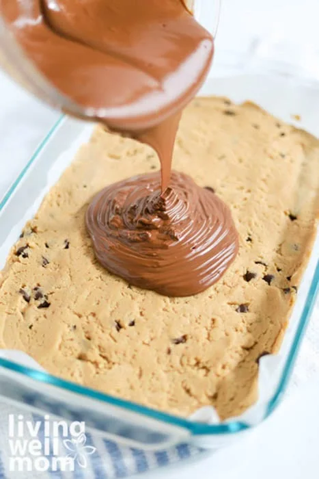 pouring layer of chocolate topping onto cookie dough filling