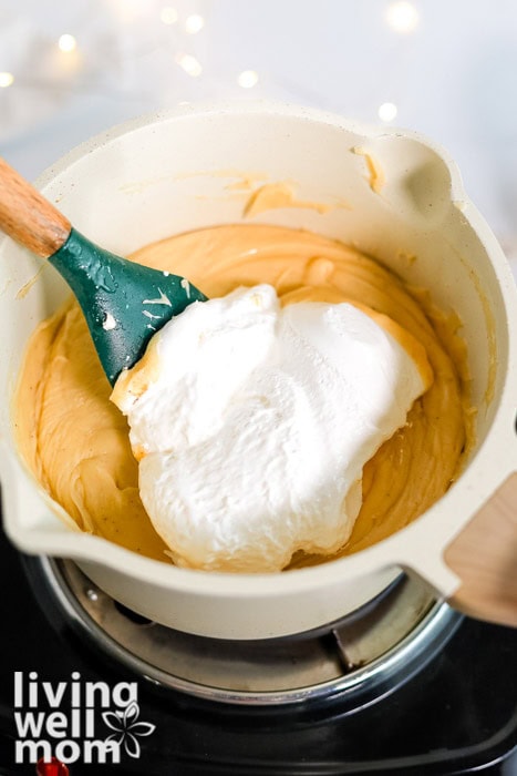 Marshmallow creme added to the fudge mixture in a saucepan.