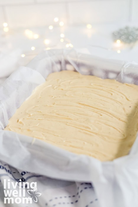 Tray of freshly chilled eggnog fudge with christmas lights in the background.