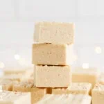 Squares of creamy eggnog fudge arranged on a plate.