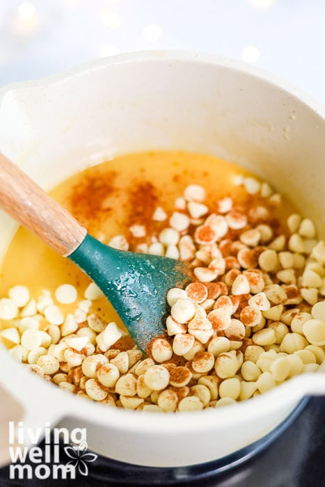 White chocolate chips and nutmeg being stirred into a saucepan