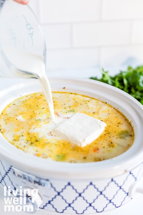 Pouring milk into creamy chicken and wild rice soup in the slow cooker