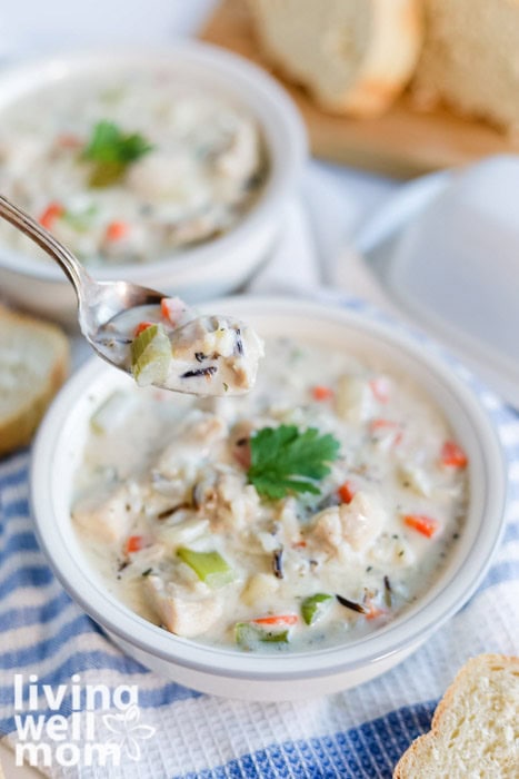 A spoonful of creamy chicken and wild rice soup with chunks of chicken and vegetables