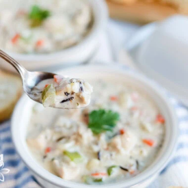 A spoonful of creamy chicken and wild rice soup with chunks of chicken and vegetables