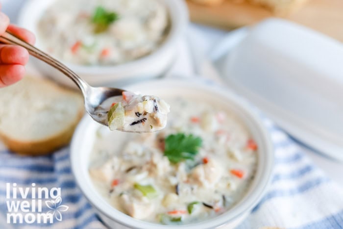 A spoonful of creamy chicken and wild rice soup with chunks of chicken and vegetables