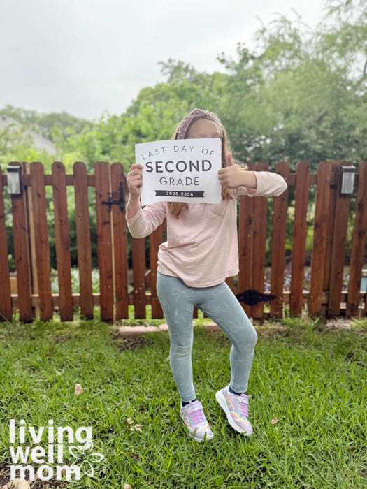 Girl holding a free printable sign for the last day of school 