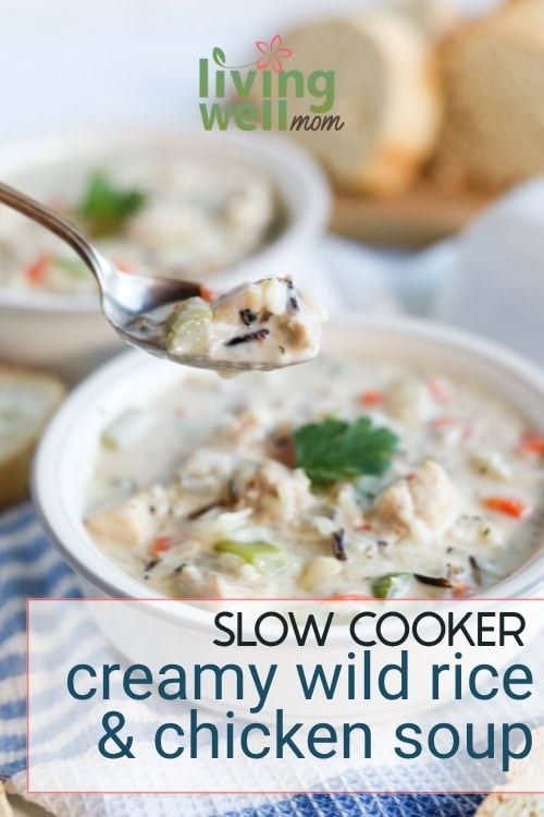 A hearty spoonful of slow cooker creamy chicken and wild rice soup with bread in background