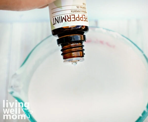 Woman pouring peppermint essential oil into soap base