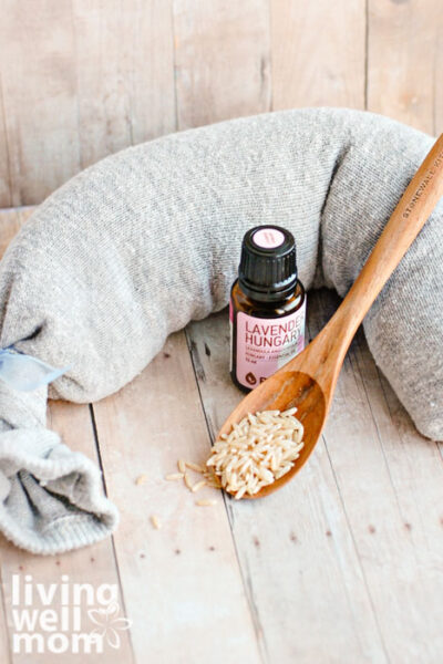 DIY heating pad with a wooden spoon filled with rice and a bottle of lavender essential oil
