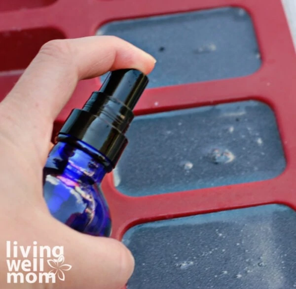 Woman spraying alcohol onto soap poured into mold to avoid bubbles