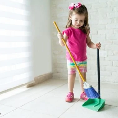 A little girl sweeping a white floor