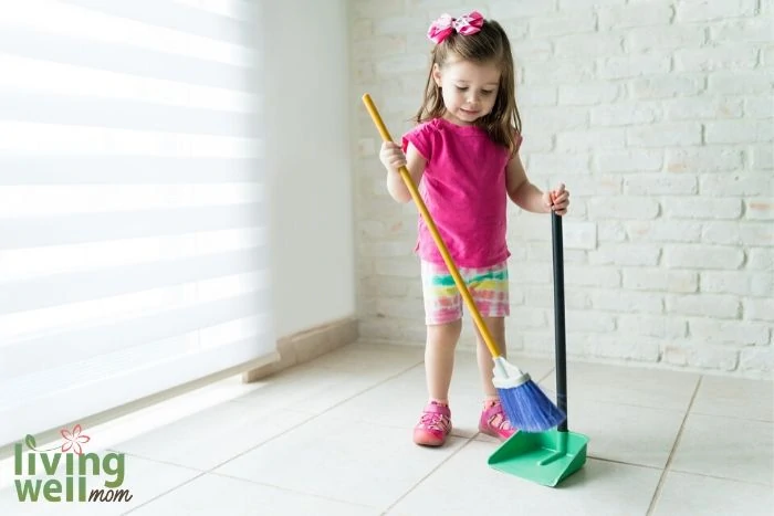 A little girl sweeping a white floor