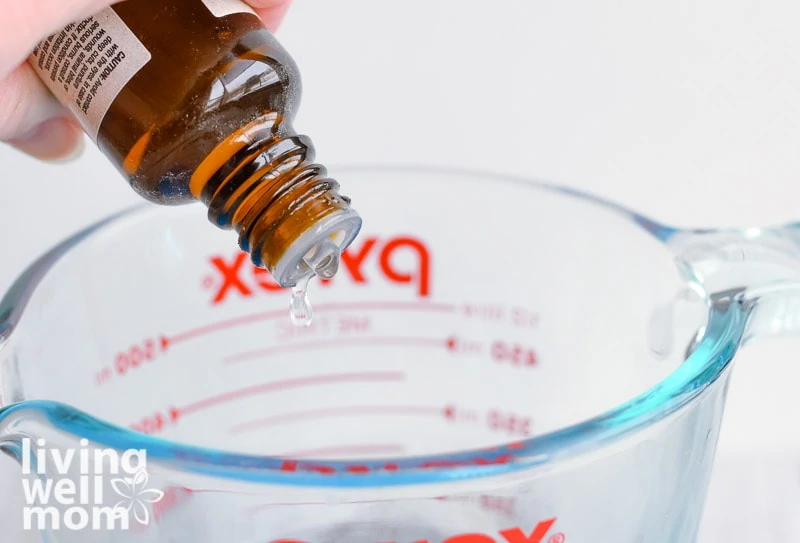 adding lemon essential oil to glass measuring cup