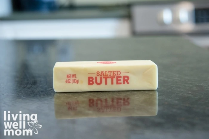 A softened stick of salted butter on a dark countertop. 