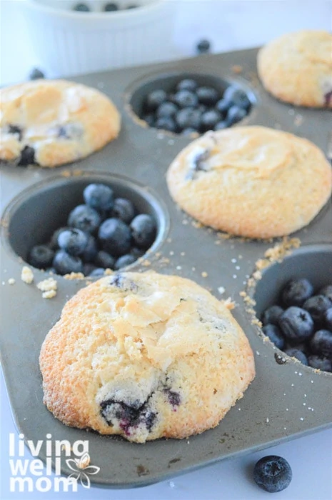 blueberry muffins in a tin with blueberries in the empty slots