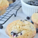 blueberry muffins cooling on a rack with a ramekin of blueberries