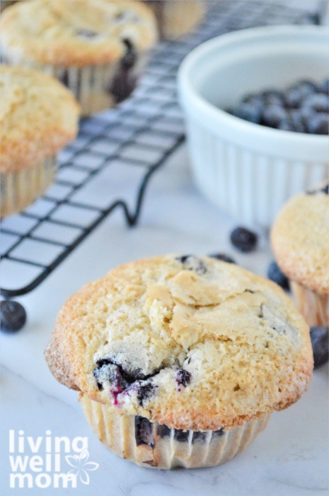 blueberry muffins cooling on a rack with a ramekin of blueberries