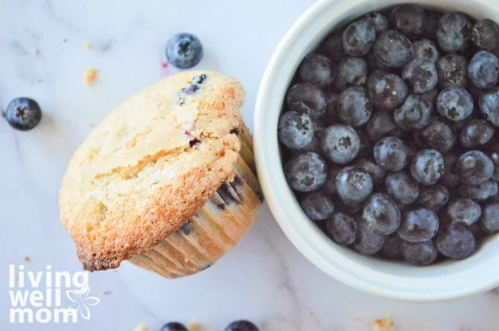 blueberry muffin sitting next to a bowl of fresh blueberries