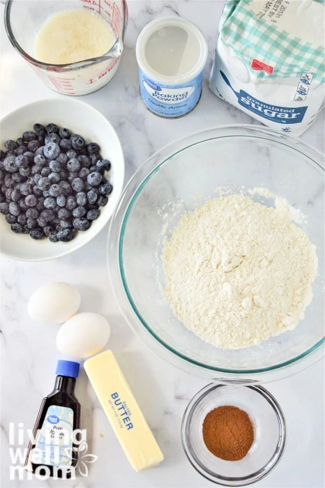 ingredients for gluten-free blueberry muffins - milk, salted butter, white granulated sugar, eggs, vanilla extract, baking powder, salt, cinnamon, nutmeg, flour, fresh blueberries